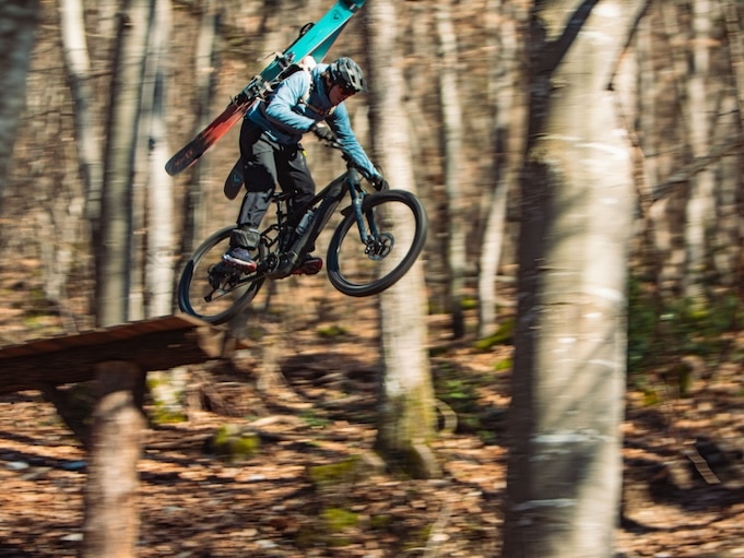 Photo of a mountain biker carrying his ski equipment