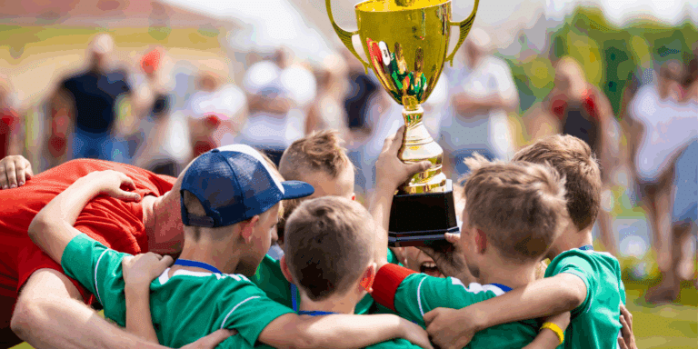 Groupe d’enfants en maillot vert tenant une coupe de vainqueur, symbole d’esprit d’équipe et de réussite sportive